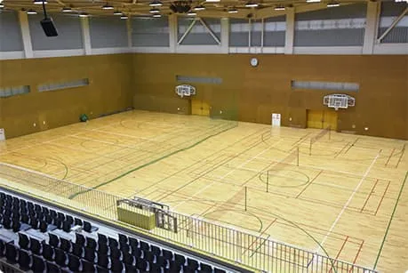 伊丹スポーツセンターの体育館競技フロア。木の床に競技ライン、バスケットゴールと観覧席がある。