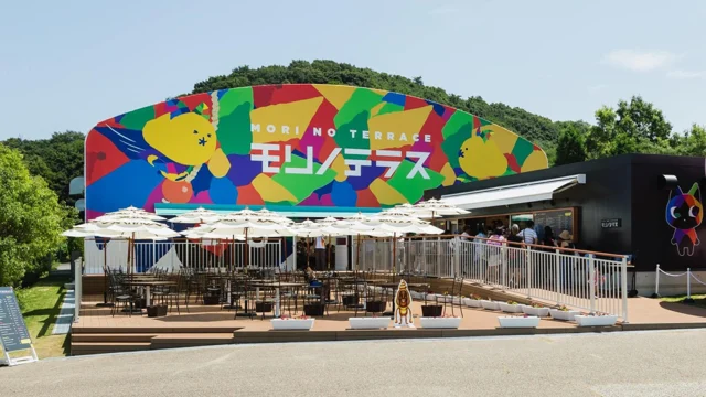 公式紹介写真のモリノテラス外観。白いパラソルが並ぶ屋外席と建物。