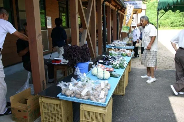 ふるさと館の軒先に野菜の販売台が並ぶ日曜朝市うえやま。町掲載写真、撮影年不明