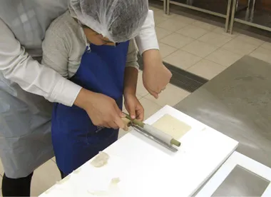 すり身を棒に巻き付けるちくわ作りの作業。ヤマサ蒲鉾公式公開写真