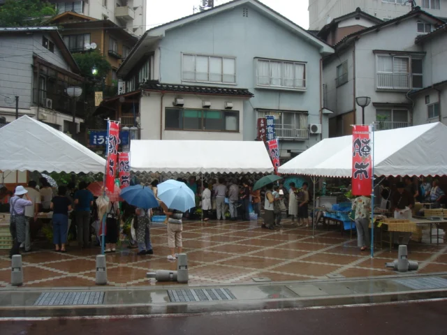 湯村温泉ポケットパークに白いテントと販売台が並ぶ朝市。町掲載の写真で撮影年不明
